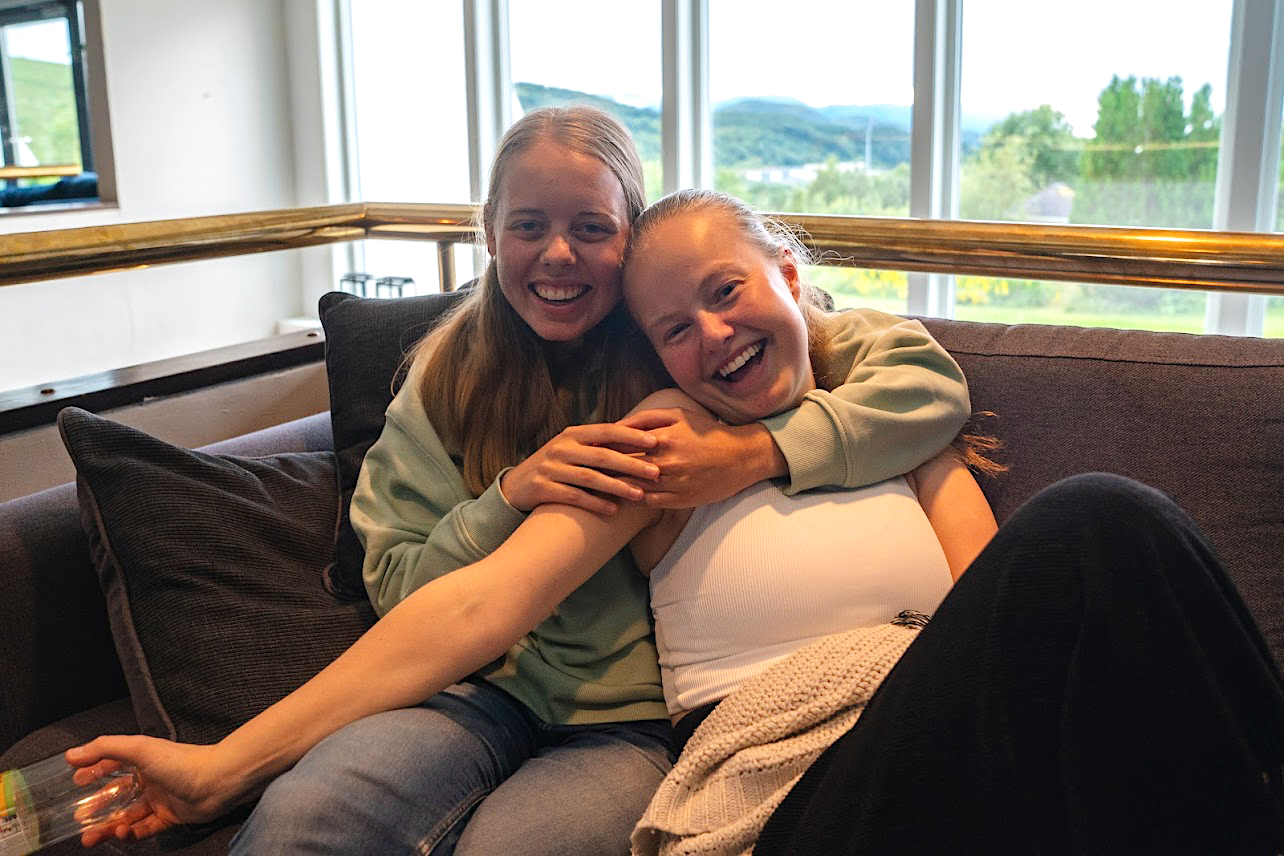 Foto av to jenter i sofa hvor en holder rundt den andre. 