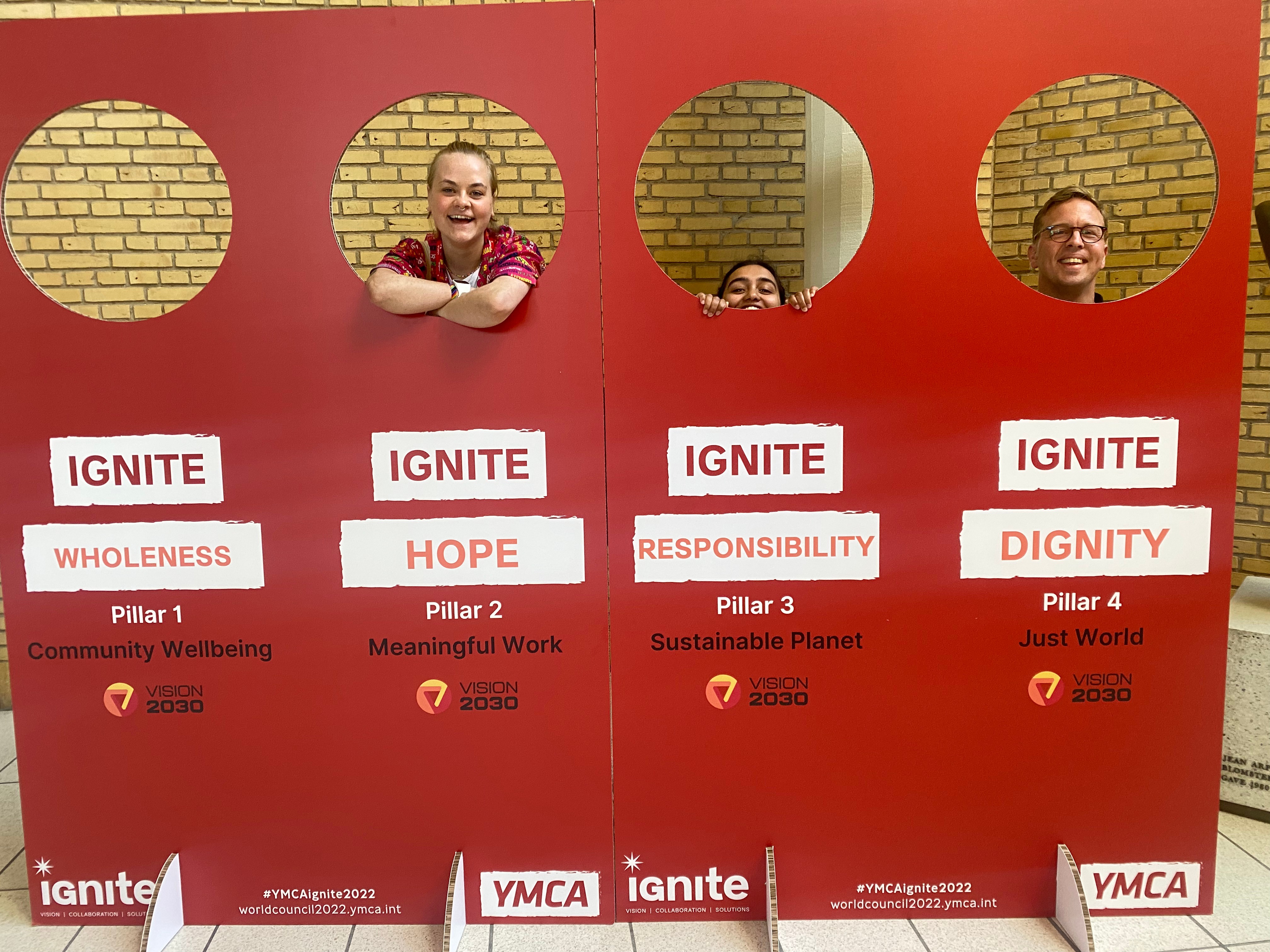 Tre perosner bak papplakat. Foto