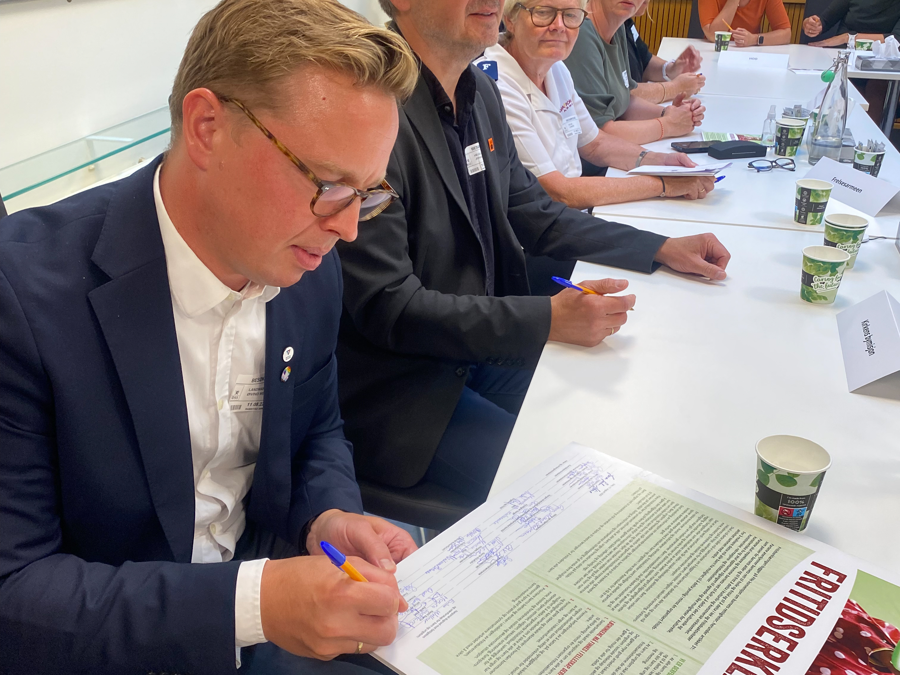 Dresskledd generalsekretær signerer fritidserklæringen. Foto