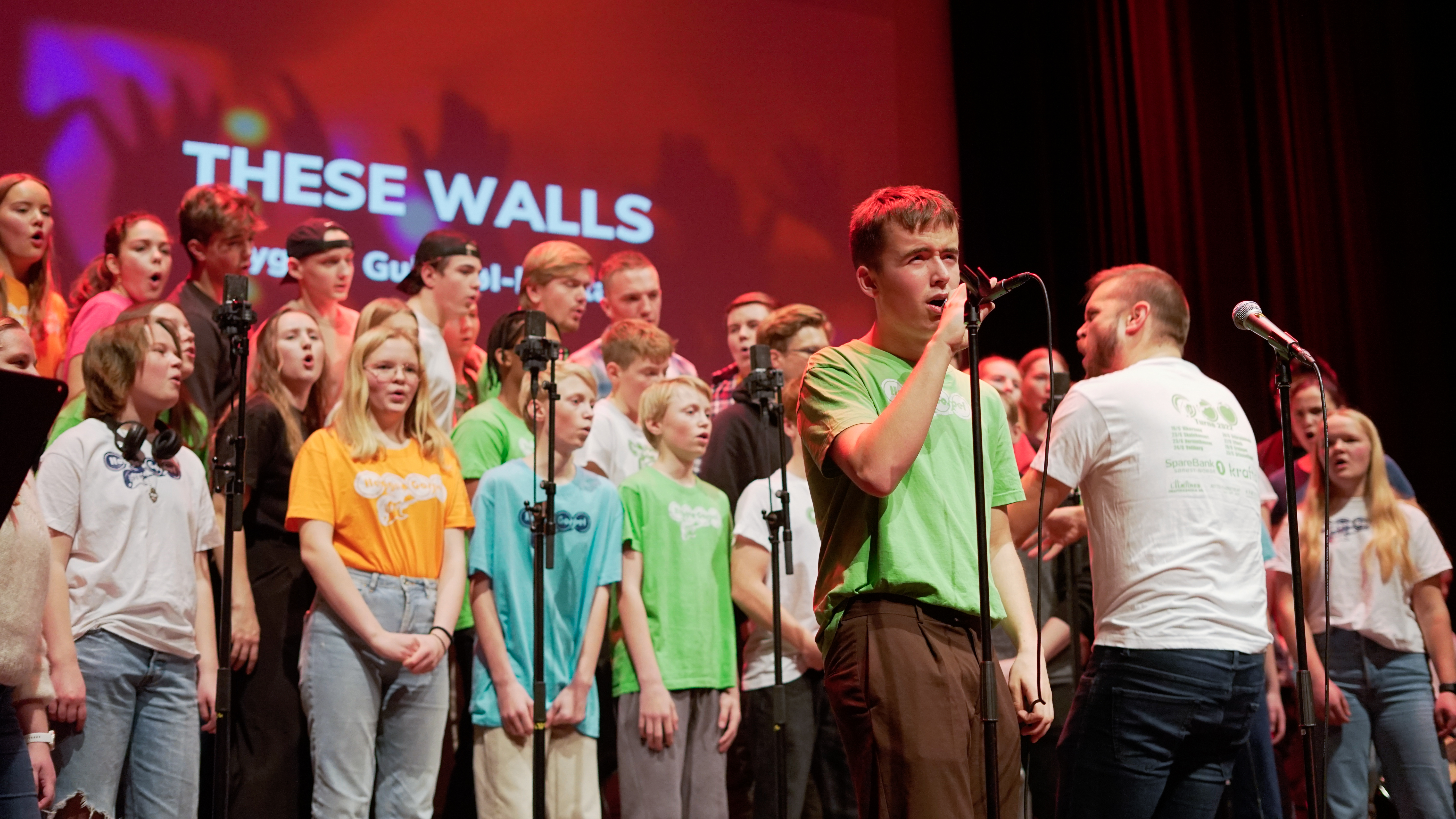 Kor på scene. Forsanger ved mikrofon.